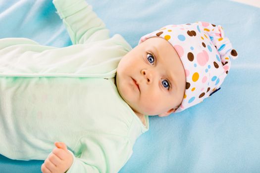 Portrait of a baby in a cap on a blue blanket
