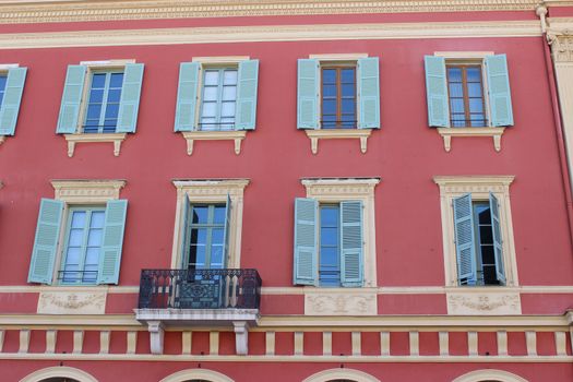 Beautiful pink facade of a building. Blue Shutters. Place Massena in Nice, France
