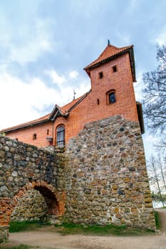 Side view of Trakai Castle with high stonewalls, on cloudy sky background.