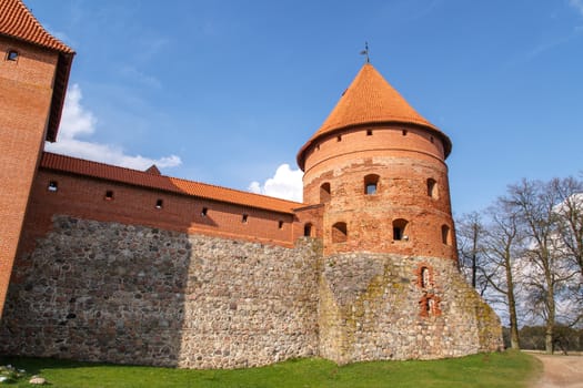 View of Trakai Castle with brown bricks and stonewalls, on cloudy sky background.