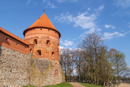 View of Trakai Castle with brown bricks and stonewalls, on cloudy sky background.