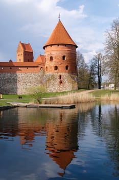 View of Trakai Castle with brown bricks and stonewalls, on cloudy sky background.