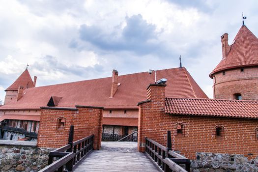 View of Trakai Castle and buildings of it in Lithuania with high brown brickwalls, on cloudy sky background.