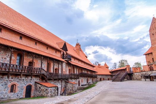 View of Trakai Castle and buildings of it in Lithuania with high brown brickwalls, on cloudy sky background.