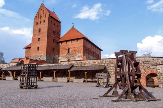 View of Trakai Castle and buildings of it in Lithuania with high brown brickwalls, on cloudy sky background.