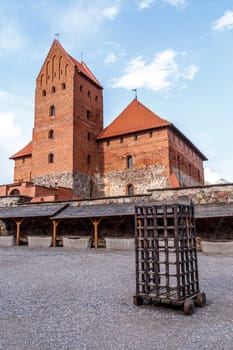 View of Trakai Castle and buildings of it in Lithuania with high brown brickwalls, on cloudy sky background.