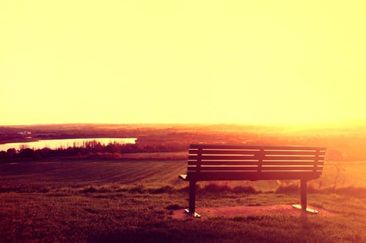 Landscape conceptual image. Alone bench at sunset.