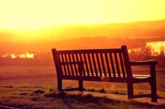 Landscape conceptual image. Alone bench at sunset.