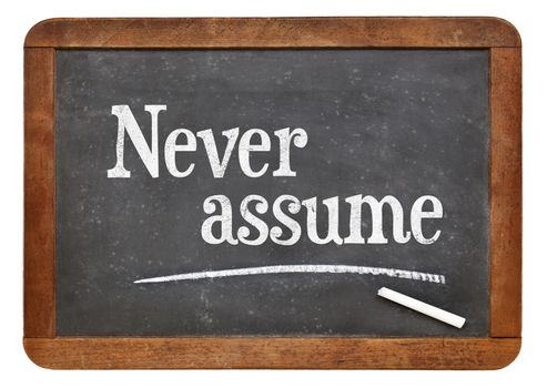 Never assume advice  - text in white chalk on a vintage slate blackboard