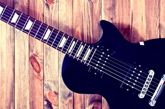 Guitar conceptual image. Picture of electric guitar lying on wooden background. Retro vintage instagram picture.