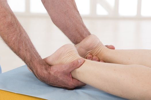 Physiotherapist stretching his patients leg in medical office