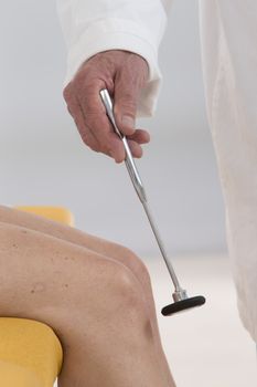 neurologist testing knee reflex on a female patient uwith  a hammer