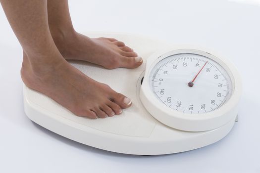 Woman stands on weighing scales isolated on white