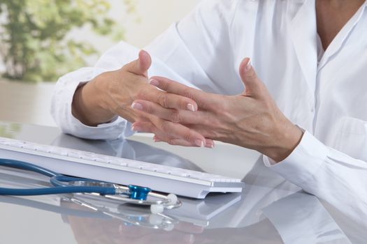 Closeup of hands of female doctor typing on computer keyboard.