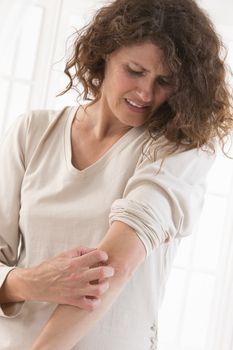 Woman suffering from  itching her arm