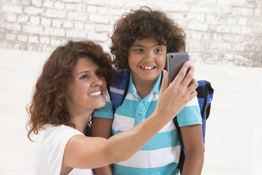 mother and sun are doing selfie by mobile phone before first day of school