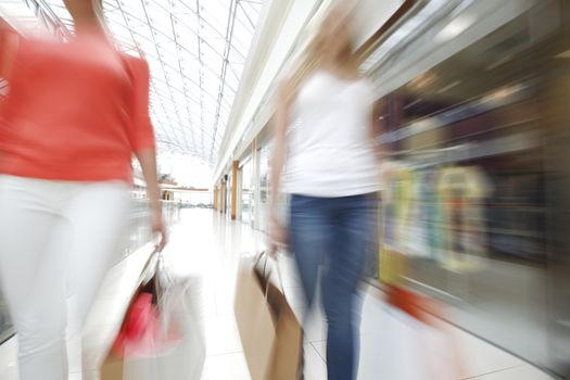 Women walking fast in shopping mall with bags