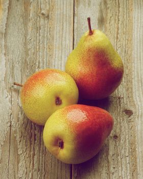 Three Fresh Raw Yellow and Red Pears isolated on Rustic Wooden background. Retro Styled