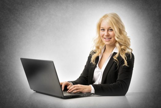 Blond happy business woman working on laptop