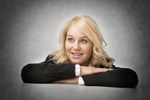 Blond smiling business woman rests her head on her arms.