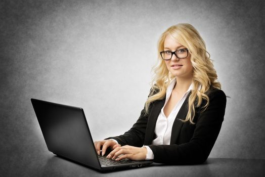 Blond business woman with glasses working on laptop