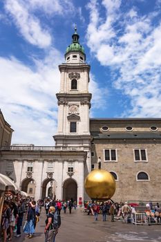 Salzburg, Austria - June 25, 2014: Modern statue at Kapitelplatz. Golden sphere, with a man standing on top, created by sculptor Stephan Balkenhol in 2007