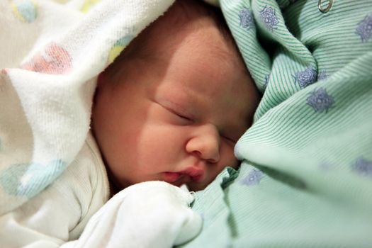 Sleeping newborn baby in the arms of my mother in hospital