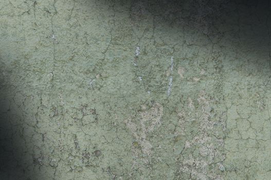 Grayish green weathered and distressed textured background wall lit diagonally