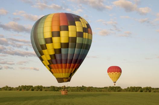 Two hot-air balloons landing in a field