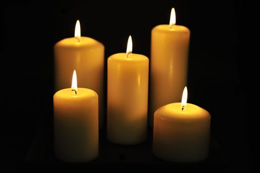 Five white candles on black background.