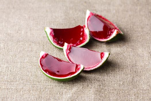 Watermelon like tequila  jelly (jello) shots made out of carved lime on linen tablecloth. Unusual adult party drinks
