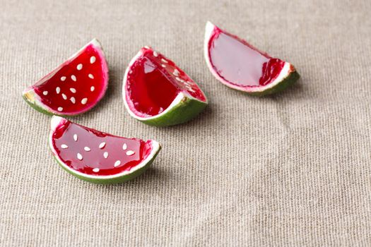Watermelon like tequila  jelly (jello) shots made out of carved lime on linen tablecloth. Unusual adult party drinks