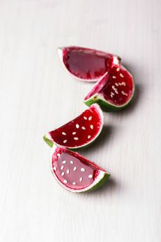 Watermelon like tequila  jelly (jello) shots made out of carved lime on bleached wooden table. Unusual adult party drinks