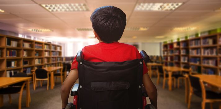 Rear view of boy sitting in wheelchair against view of library