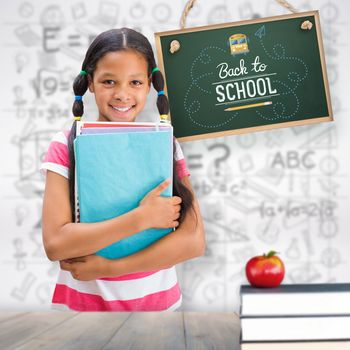 Cute pupil smiling at camera in library  against pale grey wooden planks