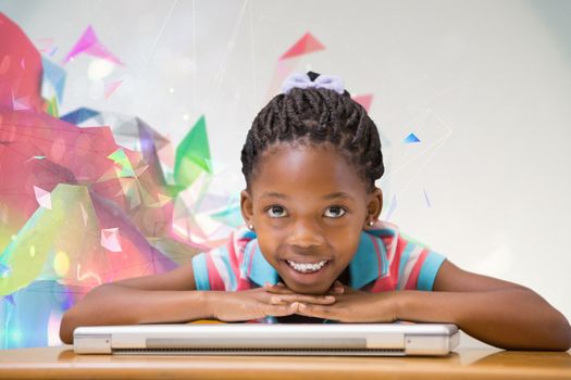 Smiling pupil sitting at her desk  against colourful abstract design