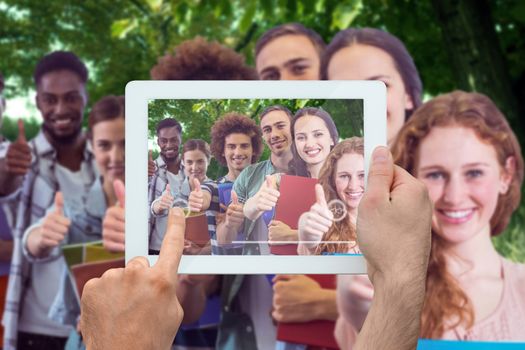 Hand holding tablet pc against park on sunny day