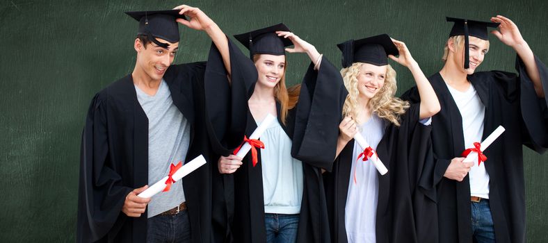 Group of teenagers celebrating after Graduation against green chalkboard