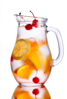 Alcoholic cocktail with orange in misted pitcher decorated with cherries.