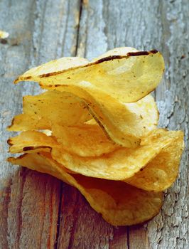 Pile of Crunchy Rosemary Potato Chips closeup on Rustic Wooden background