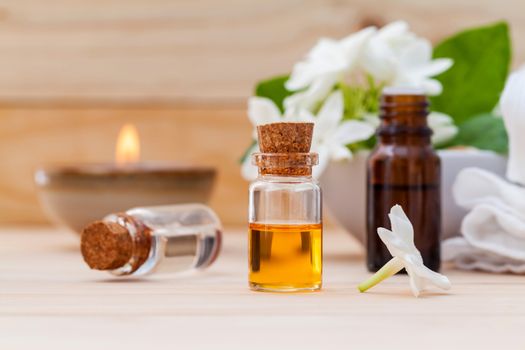 Aroma oil bottles arranged with jasmine flowers on wooden background .