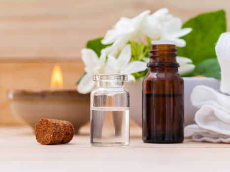 Aroma oil bottles arranged with jasmine flowers on wooden background .