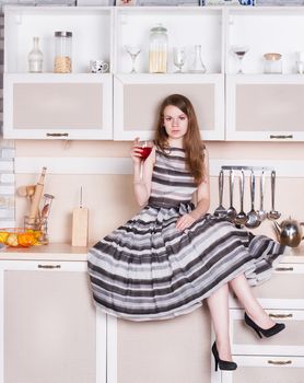 Girl in a lush gray dress sitting in the kitchen