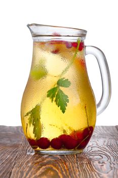 Glass pitcher of homemade spritzer (schorle) enriched with cherries and apple slices. Jug full of non-alcoholic sparkling and cold carbonated juice.
