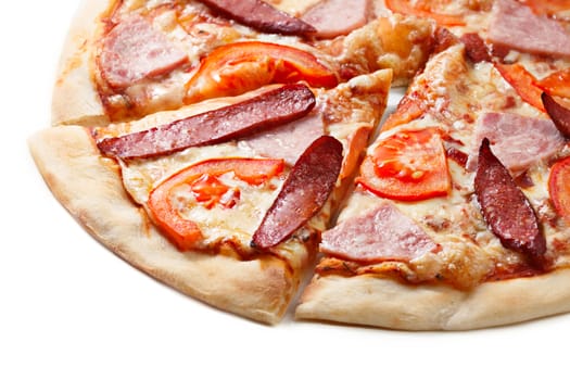 Close up of sliced pizza with tomatoes, meat and sausages