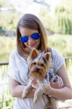 Happy young girl owner with yorkshire terrier dog walking in the park