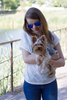 Happy young girl owner with yorkshire terrier dog walking in the park