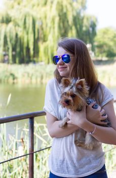 Happy young girl owner with yorkshire terrier dog walking in the park