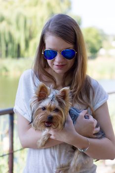 Happy young girl owner with yorkshire terrier dog walking in the park