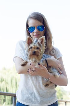 Happy young girl owner with yorkshire terrier dog walking in the park